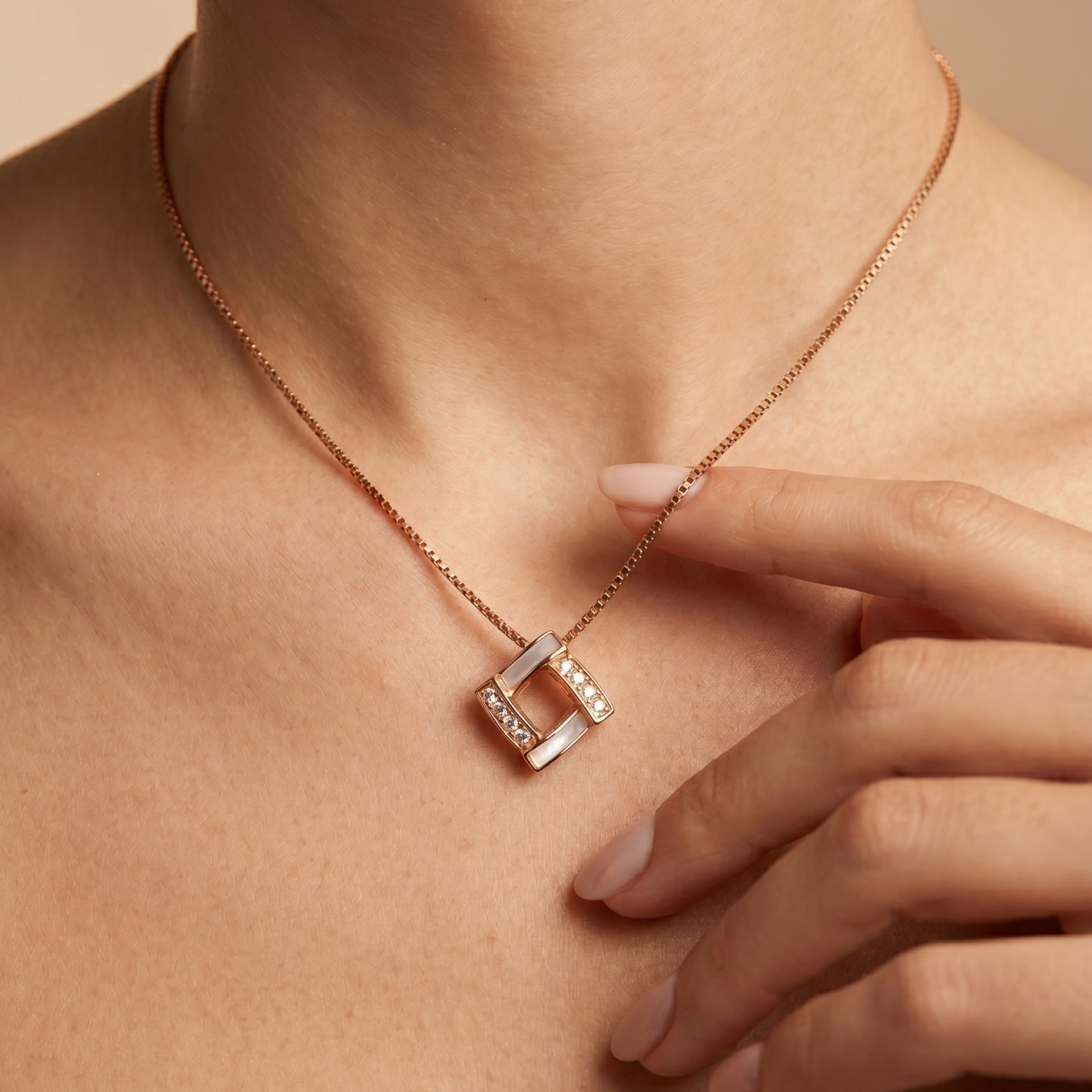 Rose gold necklace with a square pendant worn by a person