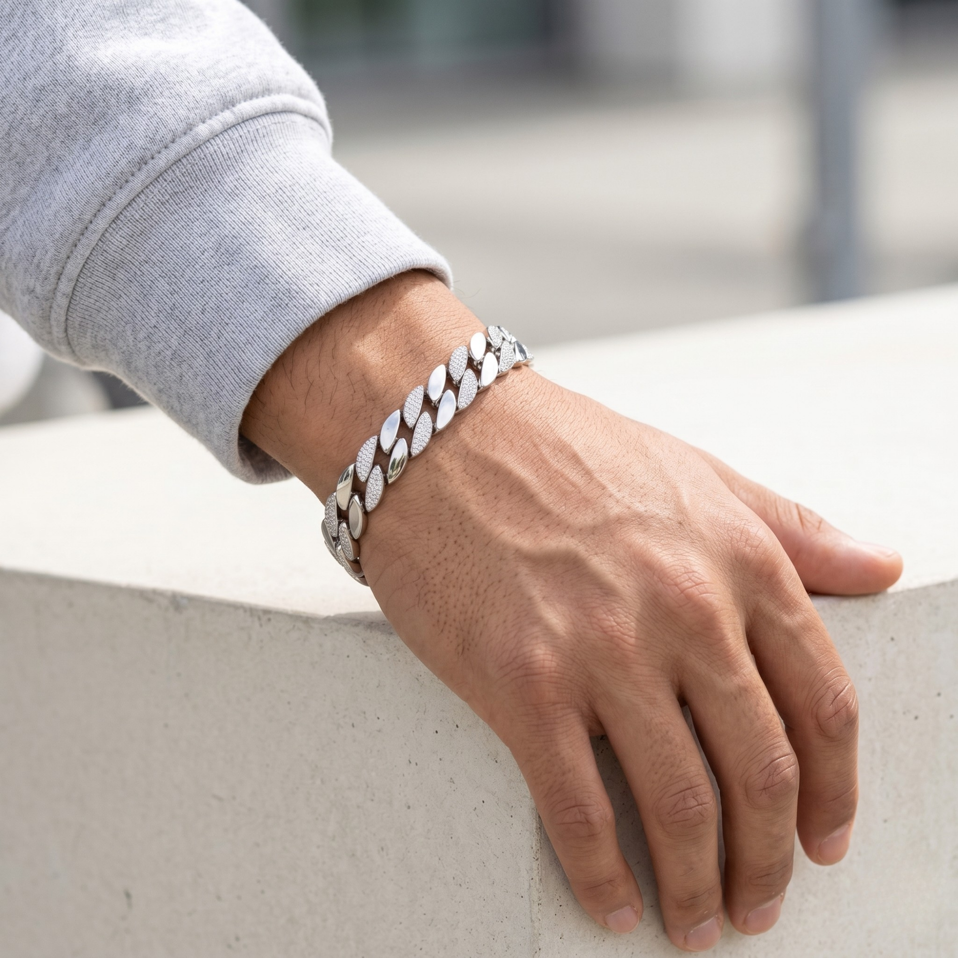 Hand wearing a silver chain bracelet on a blurred background