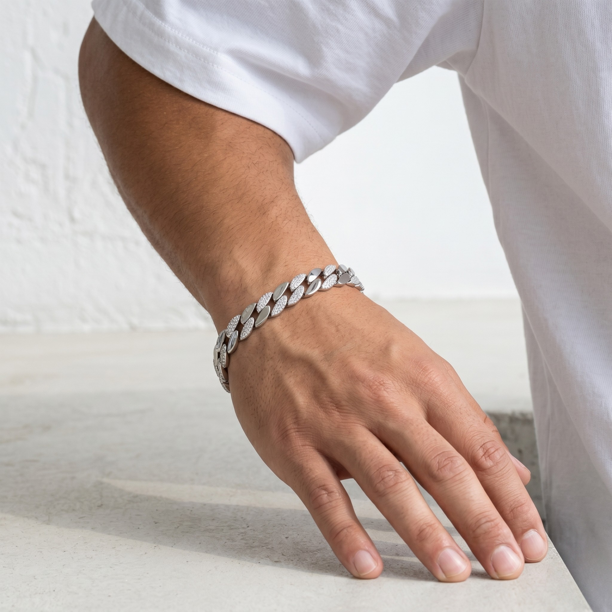 Hand wearing a silver chain bracelet on a light background