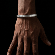 Hand wearing a silver bracelet against a black background