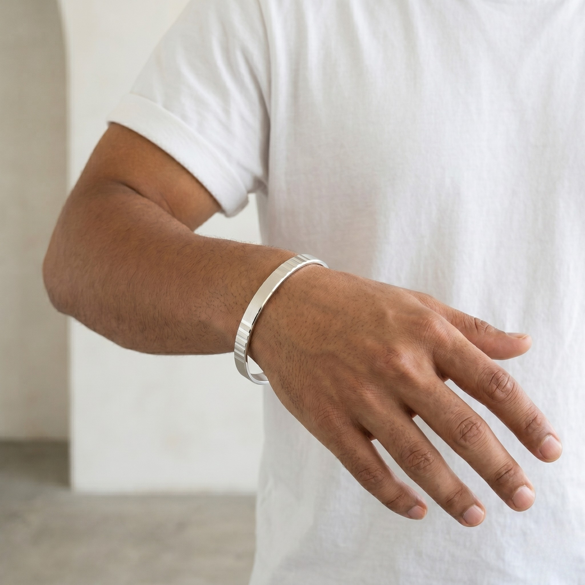 Person wearing a silver bracelet on a neutral background