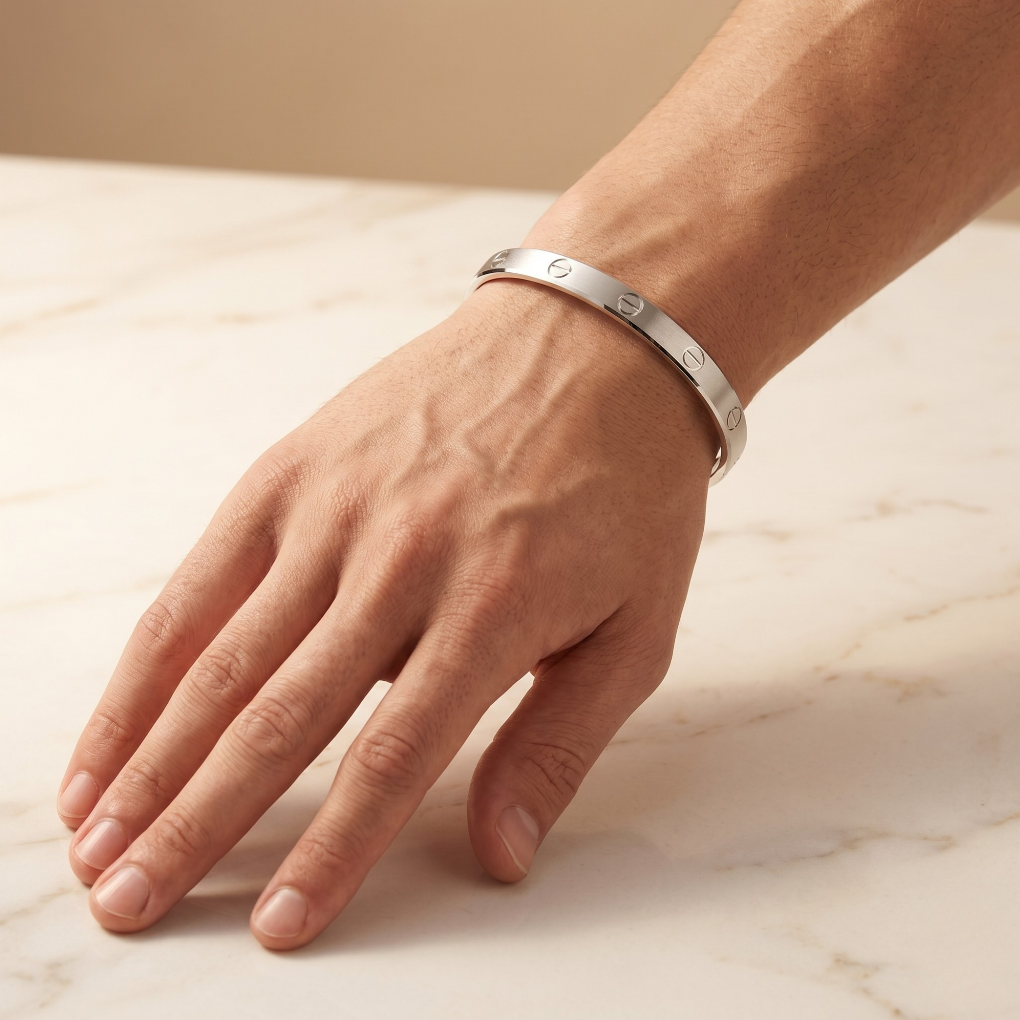 Hand wearing a silver bracelet on a marble surface