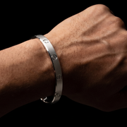 Silver bracelet on a wrist against a black background