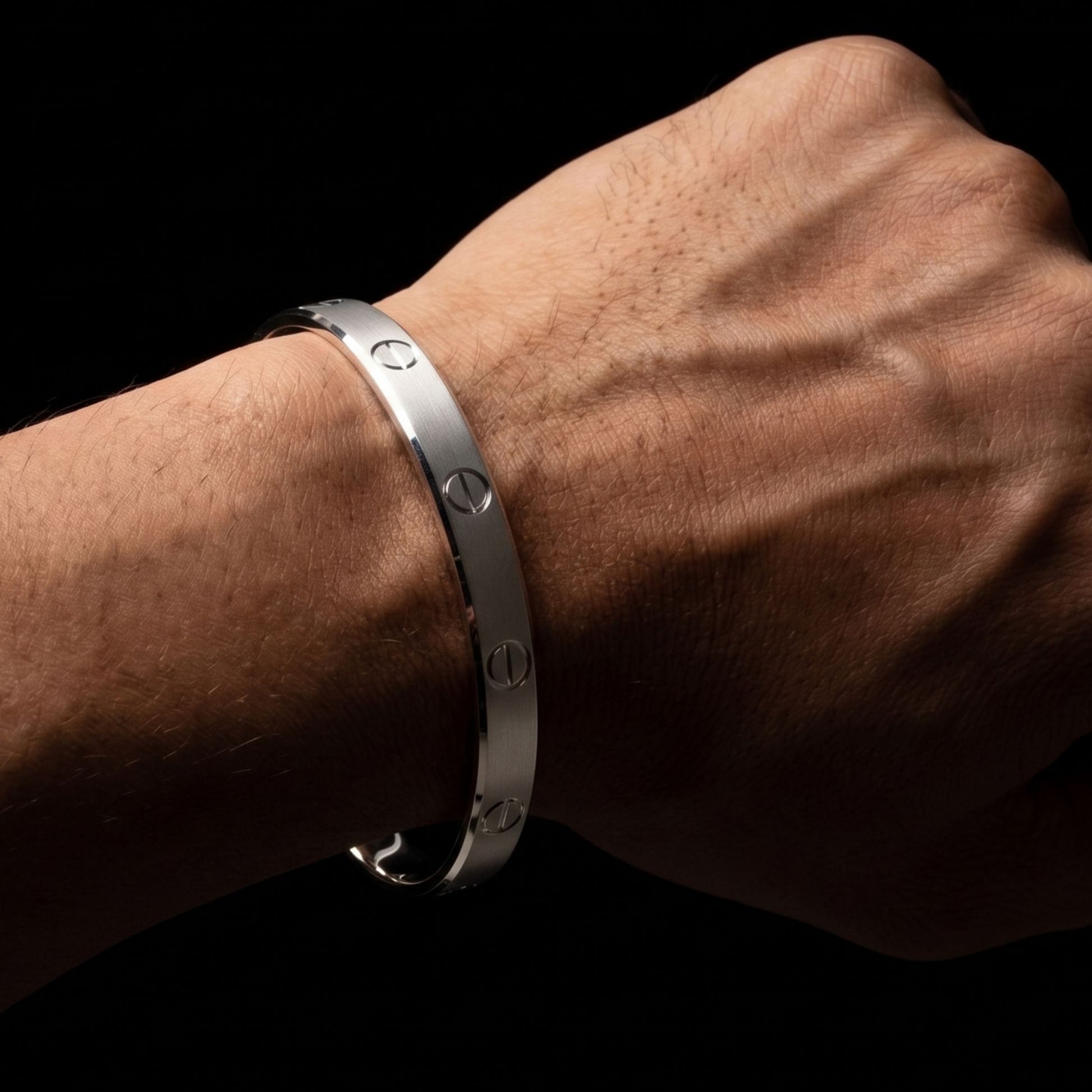 Silver bracelet on a wrist against a black background