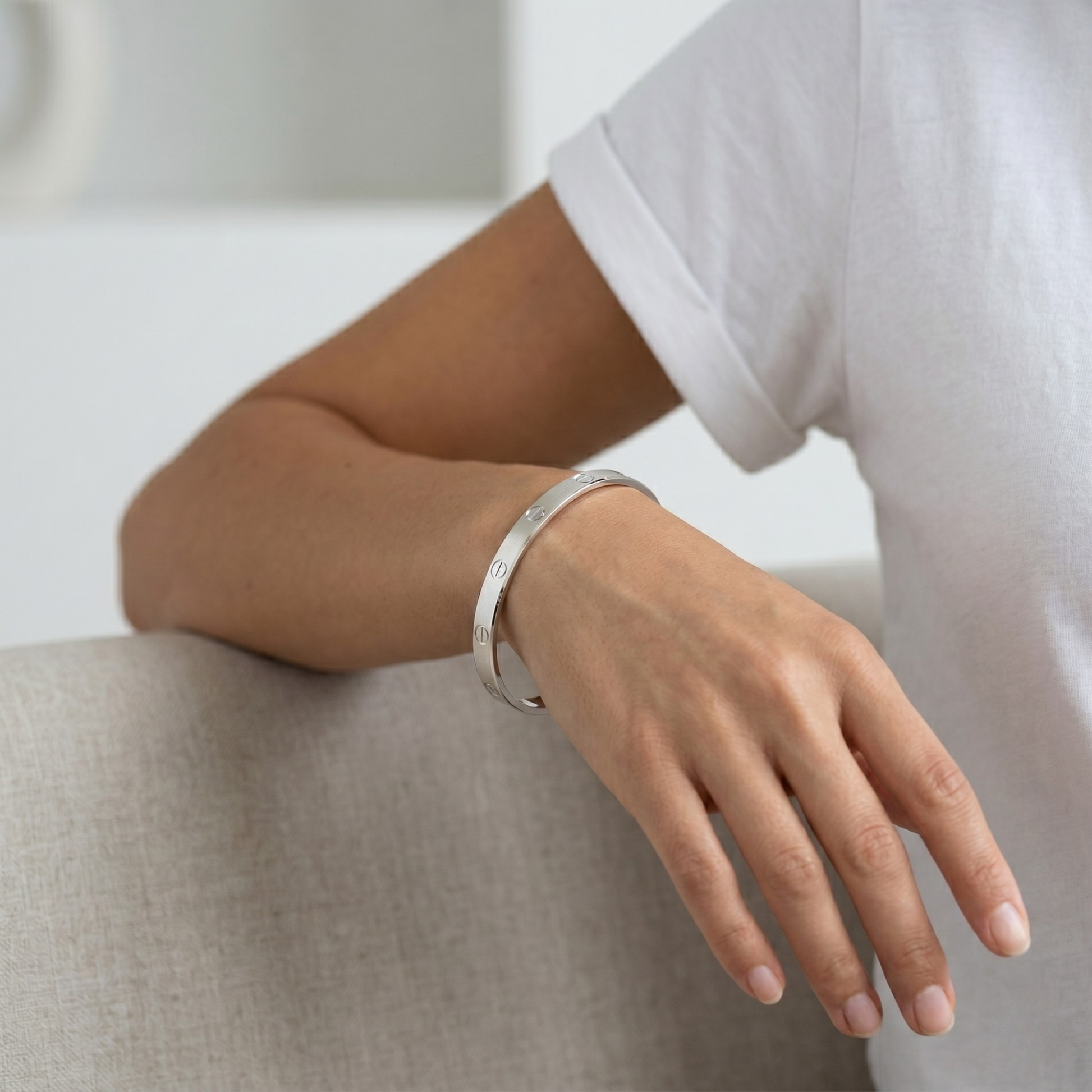 Person wearing a silver bracelet on a neutral background