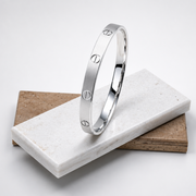 Silver bracelet with engraved design on a white stone surface