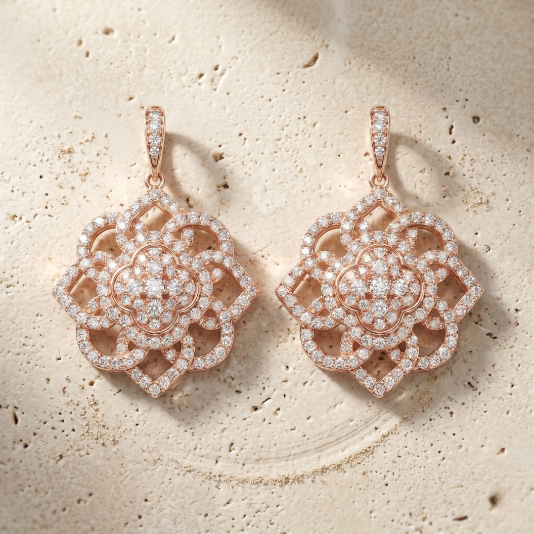 Rose gold earrings with diamond accents on a textured beige surface
