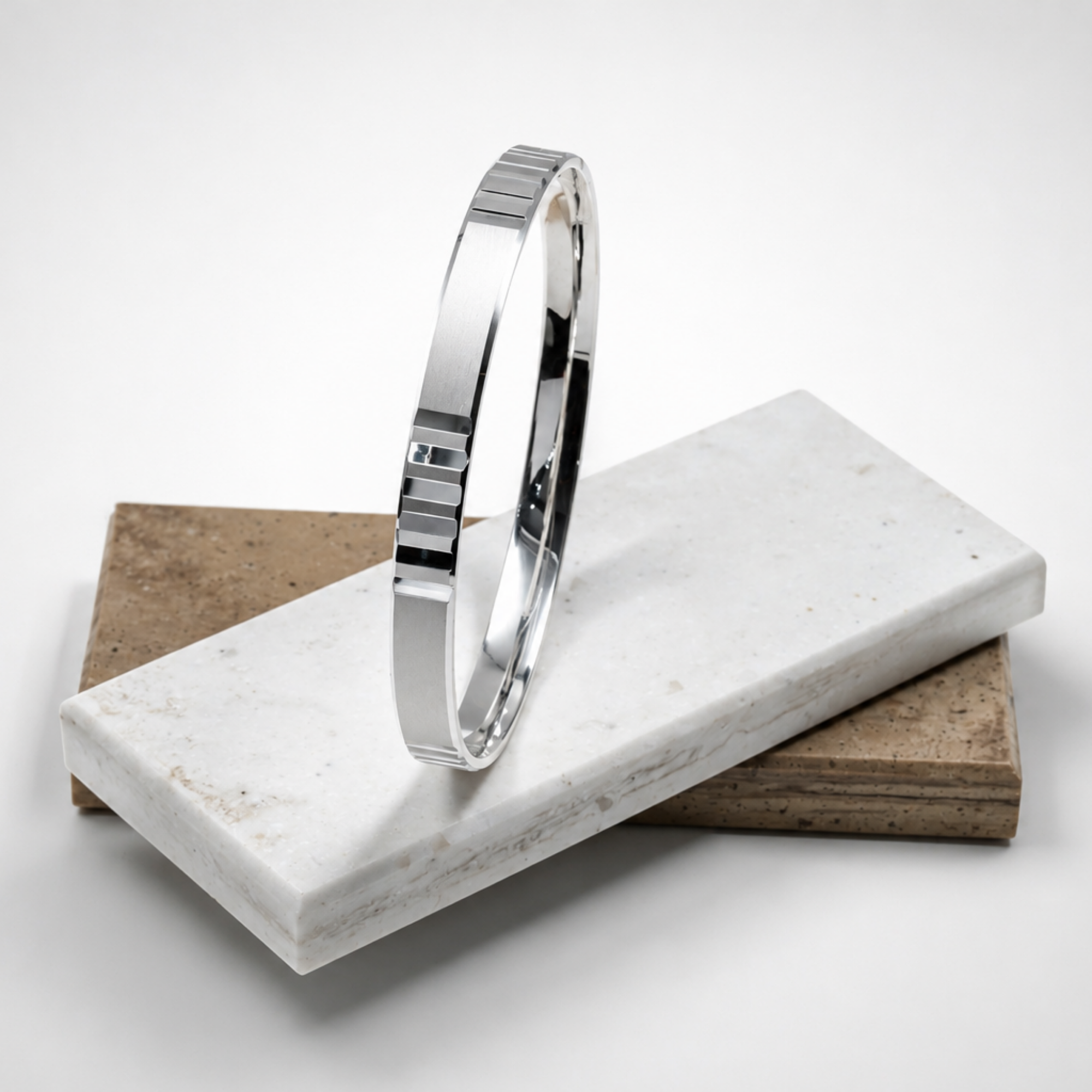 Silver bracelet on a marble stand with a white background